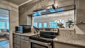 A modern kitchen with stainless steel appliances, granite countertops, and a large window providing natural light.