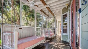 A covered porch with two wooden swing beds and a ceiling fan. - GOING COASTAL 3 Bedroom Holiday Home by Five Star Properties (Panama City Beach)