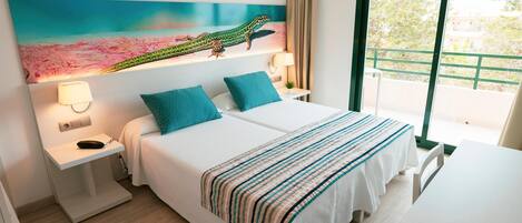 Una habitación de hotel con cama, mesitas de noche, un escritorio, una silla, un cuadro en la pared y una ventana con vistas.