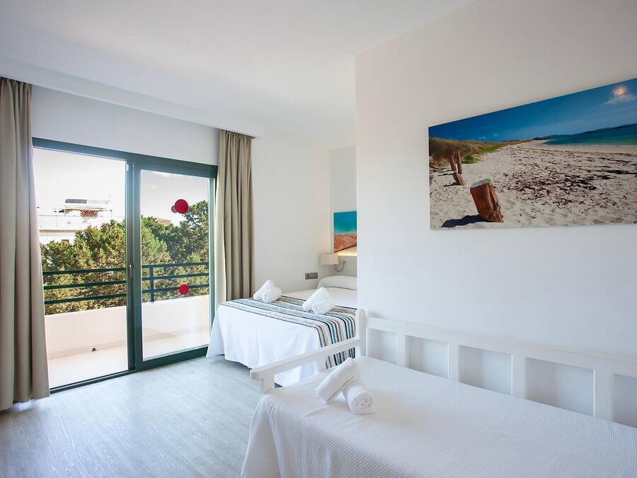 Ein Hotelzimmer mit Balkon, einem Bett, einem Gemälde und Blick auf den Strand.