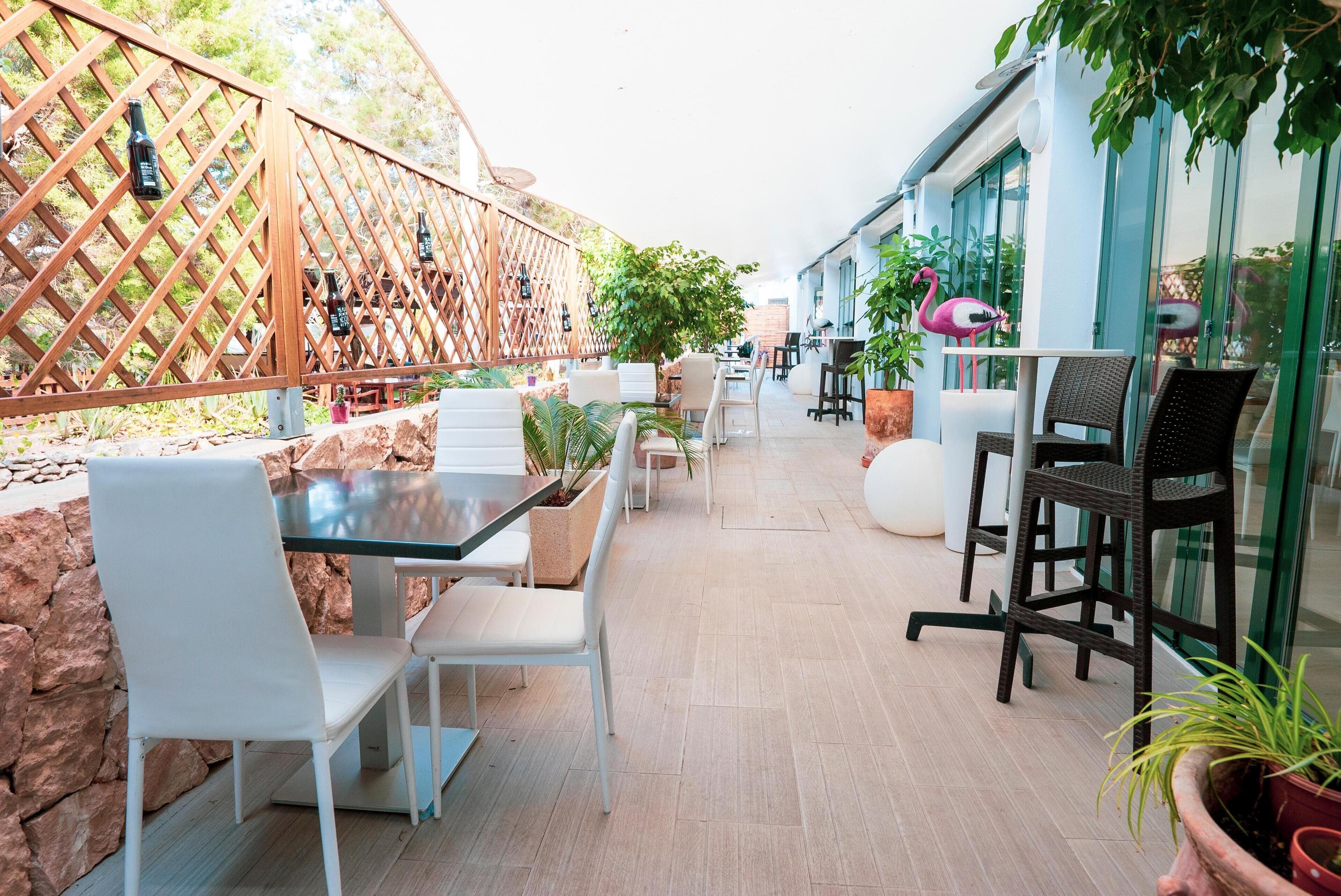An outdoor patio area with seating arrangements, a wooden fence, and potted plants.