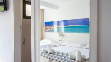 Een hotelkamer met een bed, nachtkastje en een schilderij van een strand.