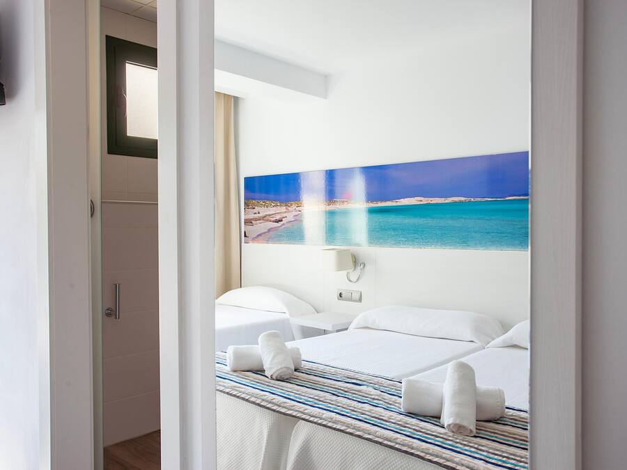 Een hotelkamer met een bed, nachtkastje en een schilderij van een strand.
