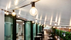 Un couloir avec des ampoules suspendues, des cloisons en verre et des tables.