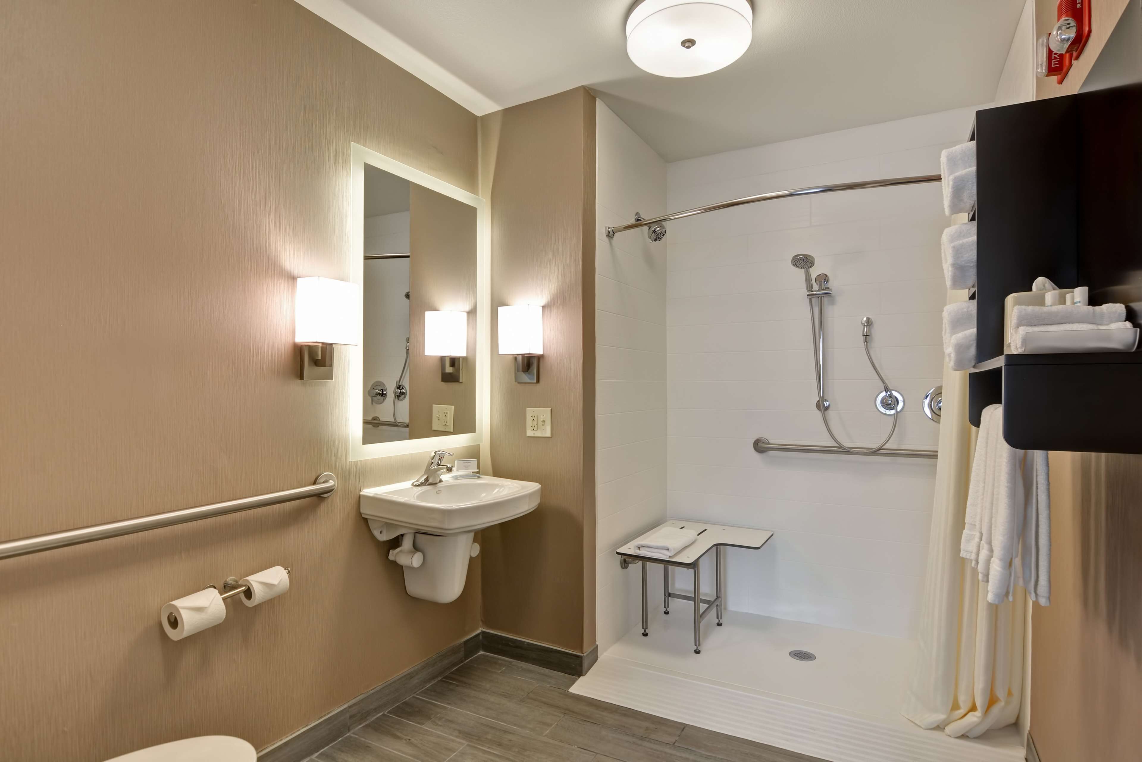 A modern bathroom with a toilet, sink, mirror, shower, and towel rack.
