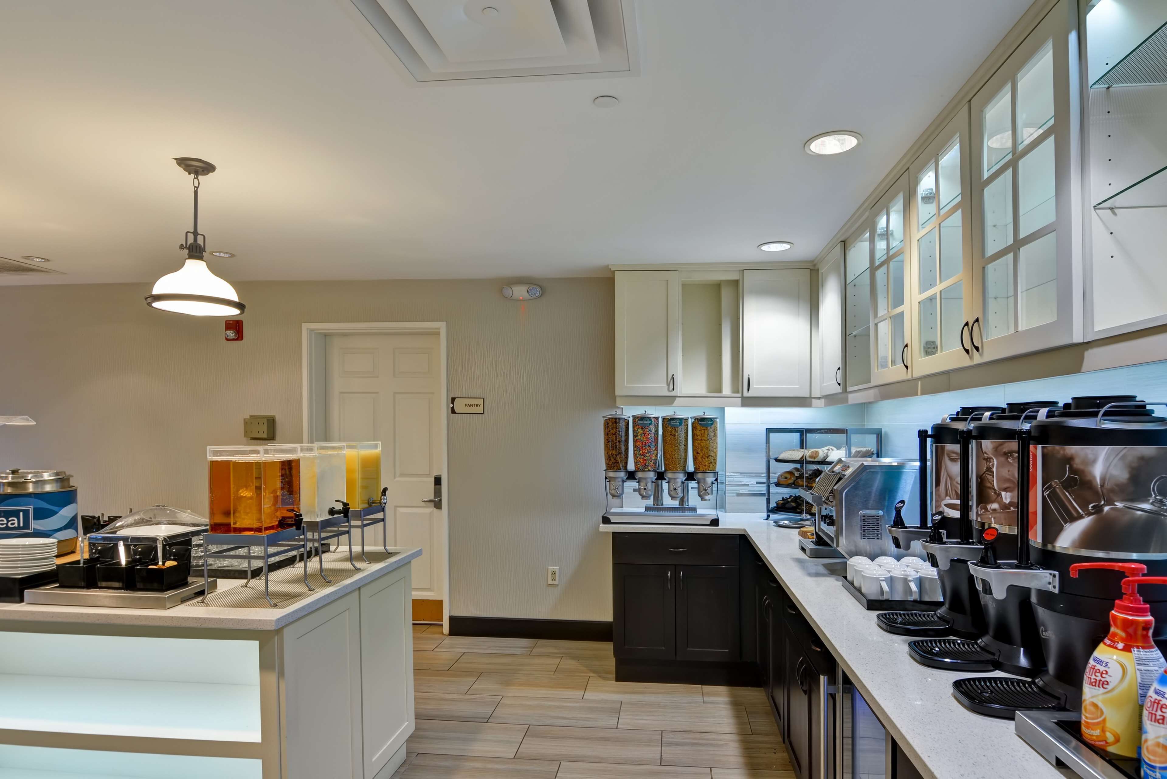A modern kitchen with a breakfast bar, coffee machines, and a juice dispenser.