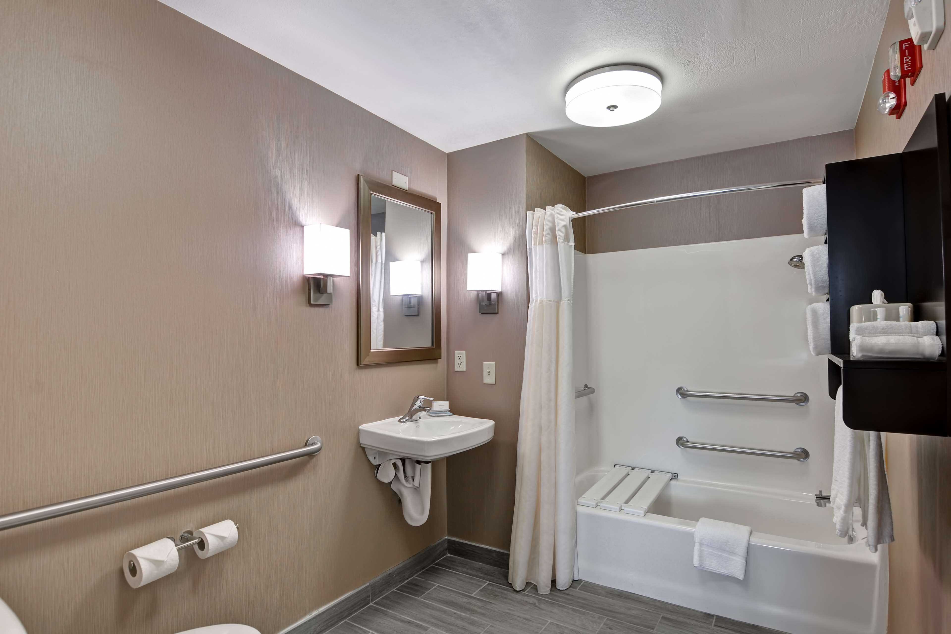 Une salle de bain équipée d’un lavabo, d’un miroir, d’un porte-serviettes, d’une douche et de toilettes.