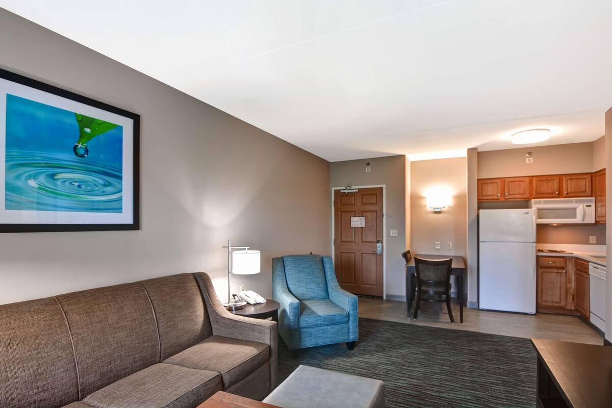 Ein Hotelzimmer mit einer Couch, einem Sessel, einem kleinen Tisch und einem Bild an der Wand.