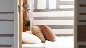 A bedroom with a bed, pillows, a bedside table, and a nightstand. - Eco Hostel - Tribo da Praia (Peniche)