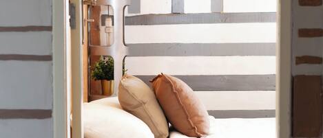Un dormitorio con cama, almohadas, una mesita de noche y un velador.