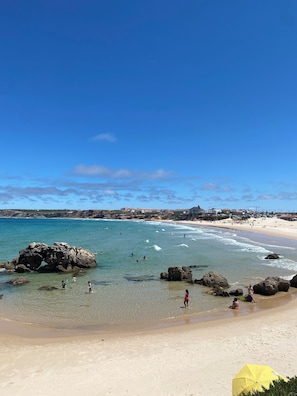 Une plage avec une eau claire, des rochers et des gens.