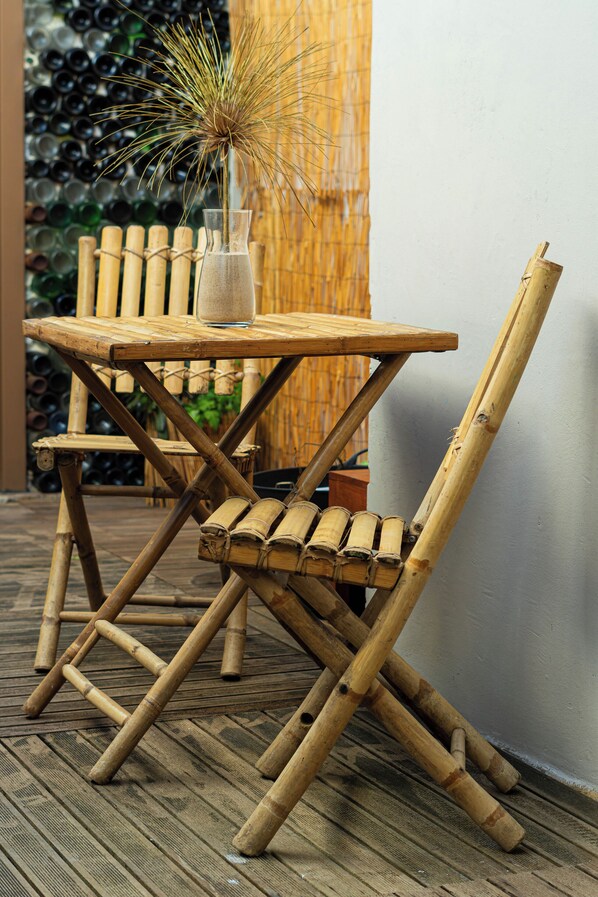 A bamboo table and chair set on a wooden deck with a bamboo backdrop. - Eco Hostel - Tribo da Praia (Peniche)