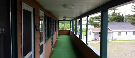 A long corridor with green carpeting, large windows, and a view of a residential area.