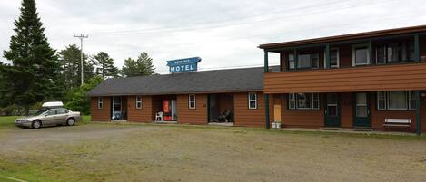 Een motel met een gebouw van twee verdiepingen, een auto voor de gevel en een bord dat de ingang aangeeft.