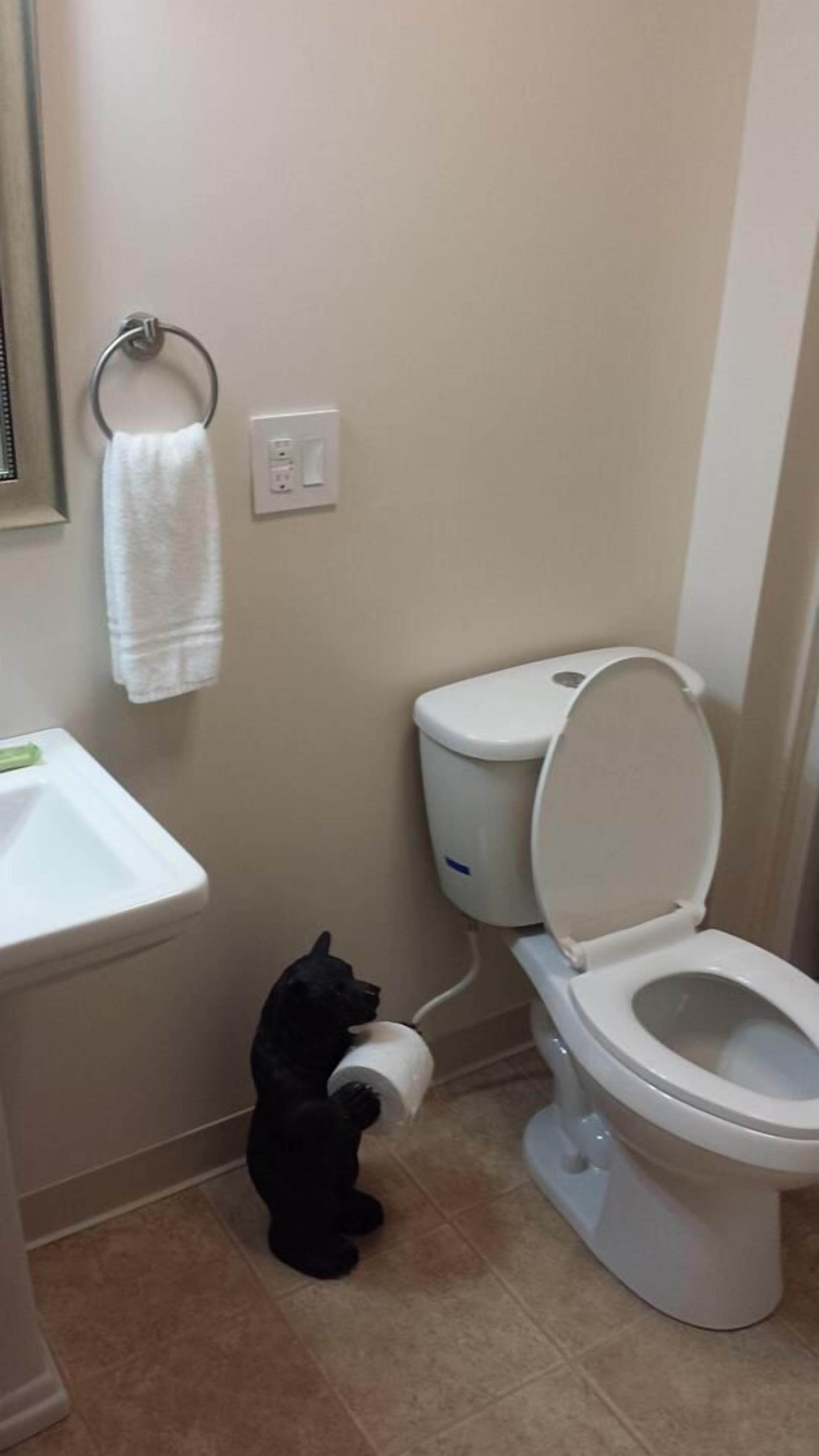 Een badkamer met toilet, wastafel en een handdoek aan een metalen ring.