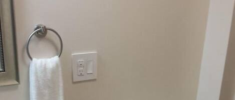 Een badkamer met toilet, wastafel en een handdoek aan een metalen ring.