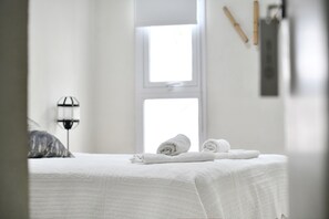 A neatly made bed with white linens and a folded towel on the side.