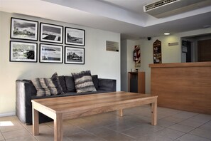 A modern living room with a wooden coffee table, a black leather sofa, and a reception desk.