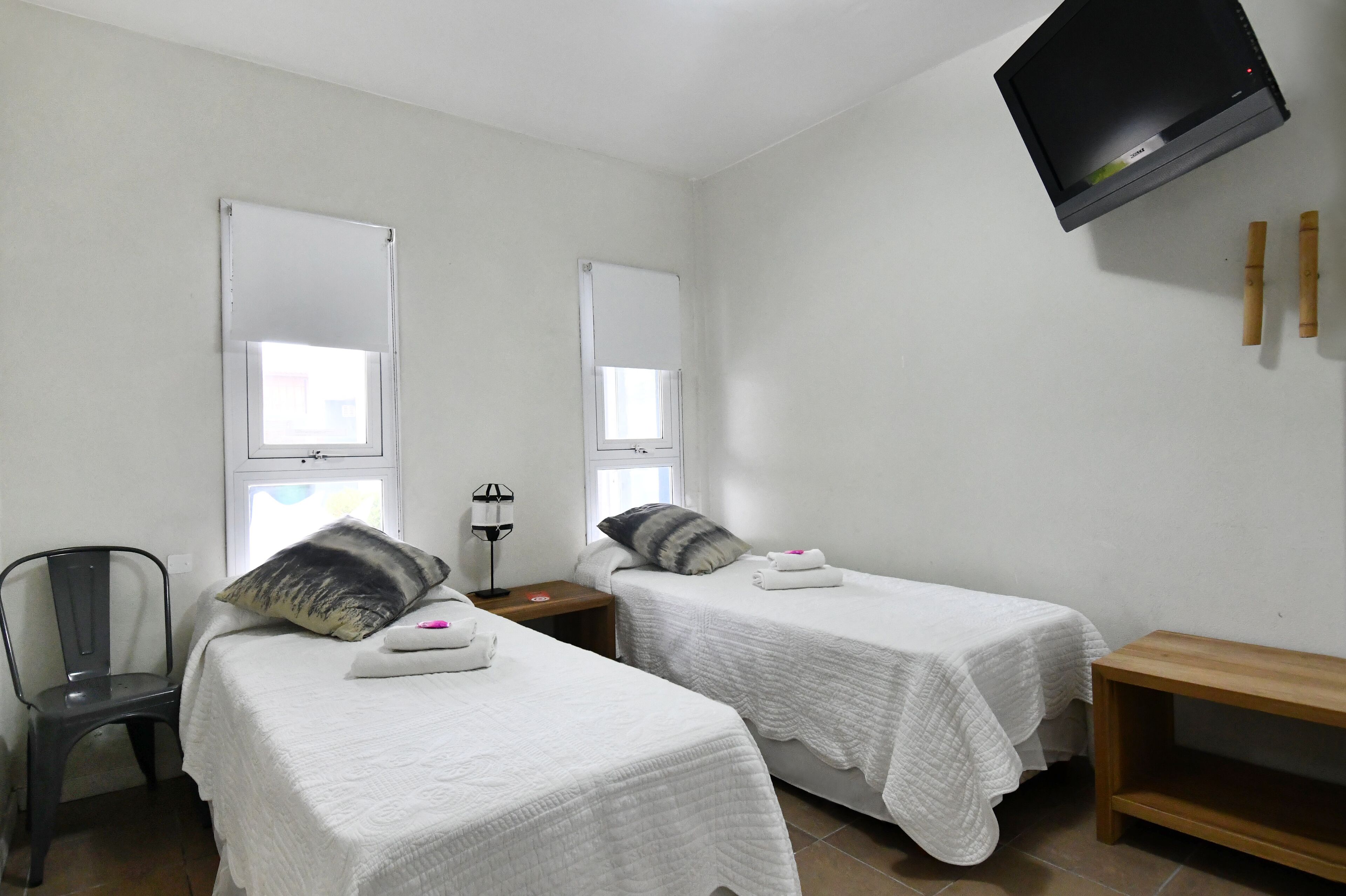 Une chambre avec deux lits, une chaise, un téléviseur et une petite table.