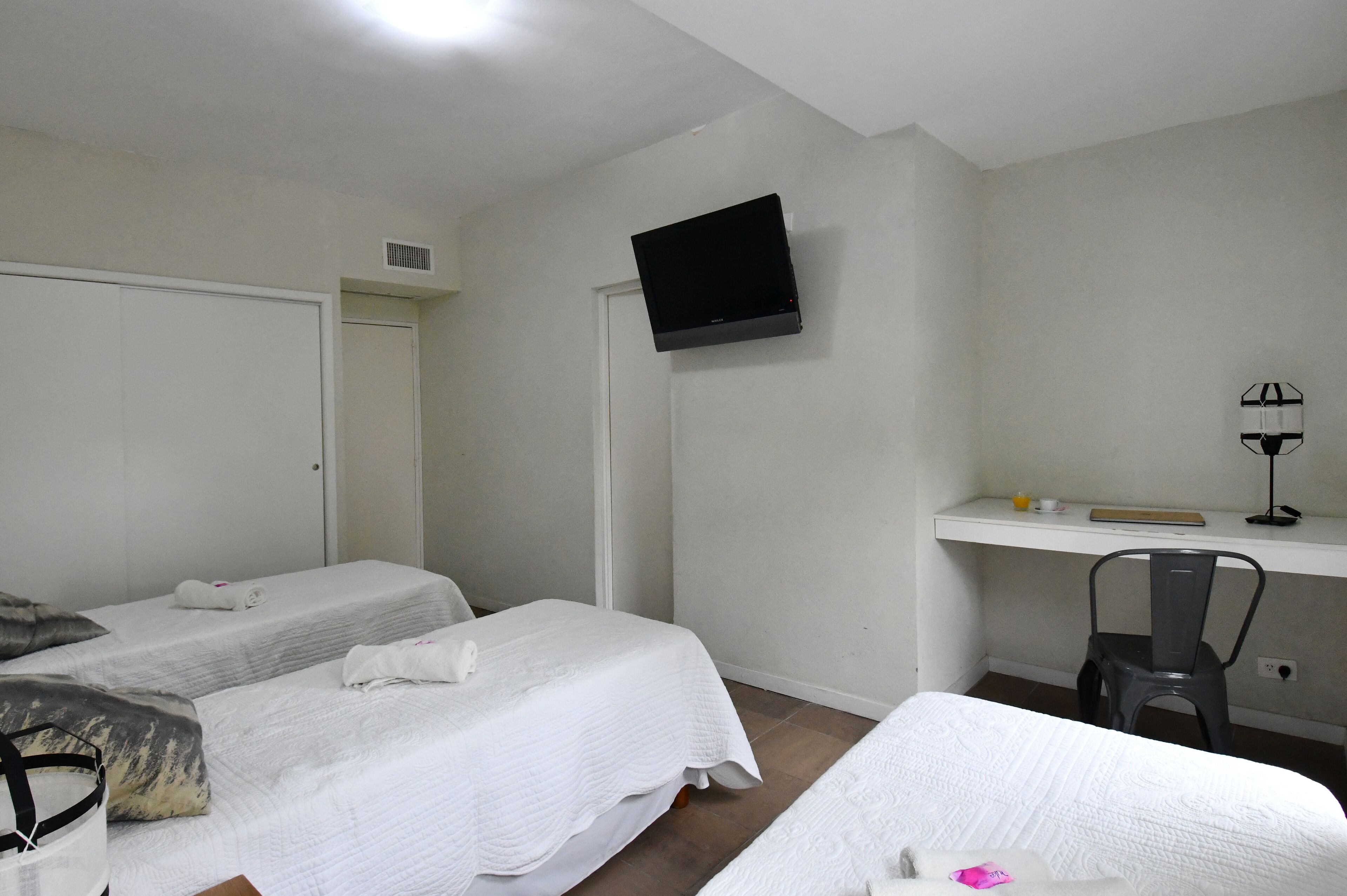 A room with two beds, a desk, a chair, a television, and a door.