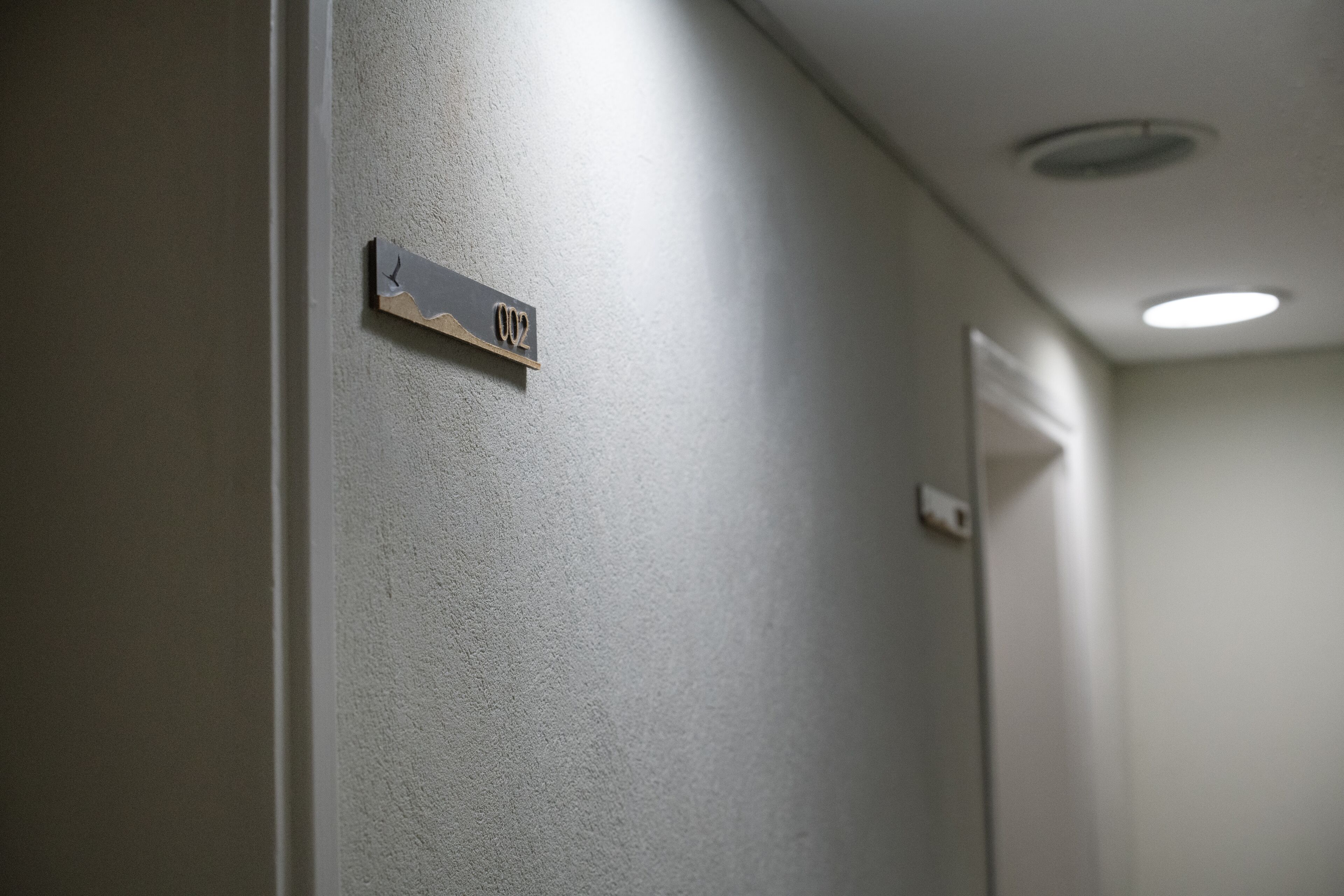 Un couloir avec une plaque fixée au mur portant l’inscription « 002 ».