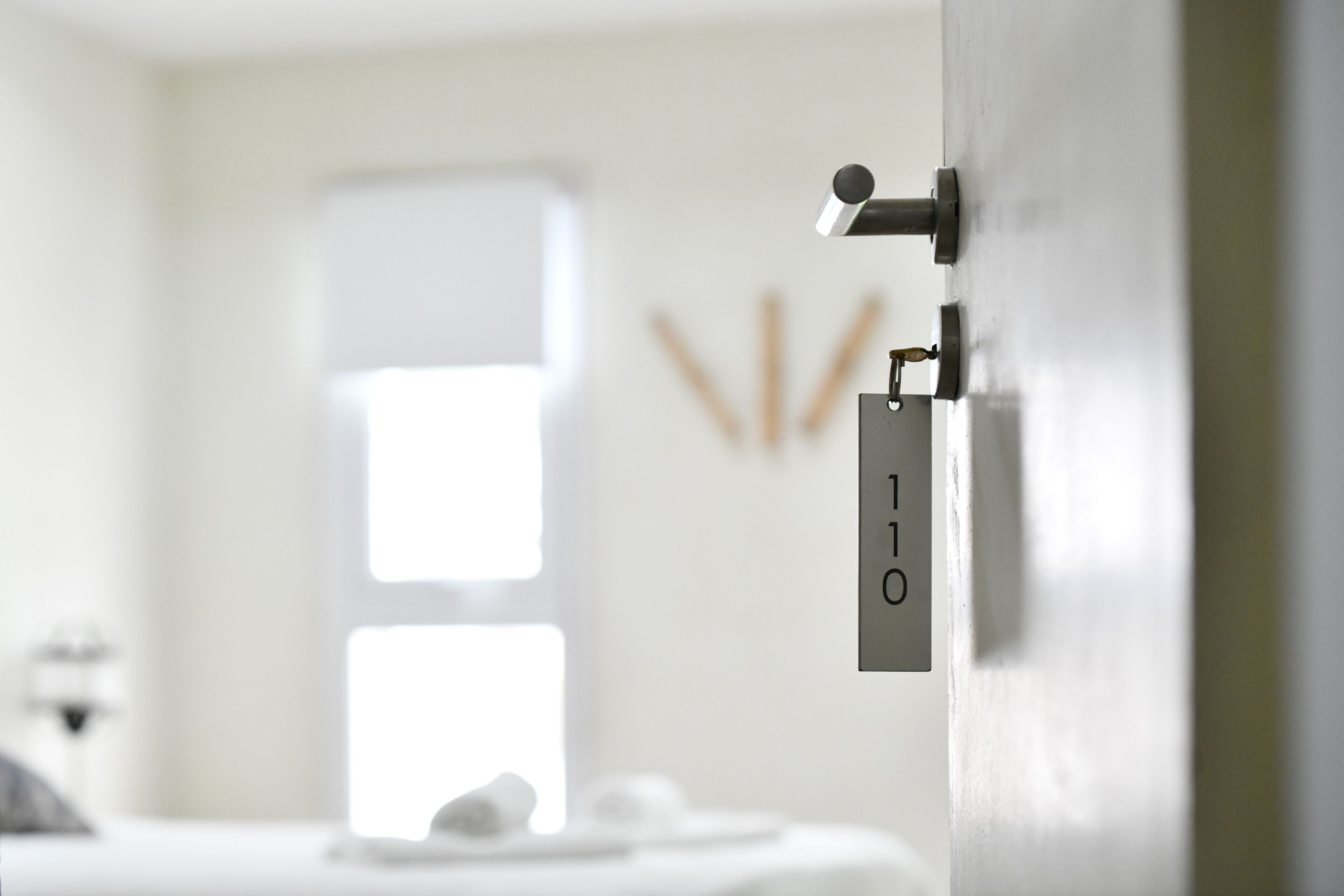 Un baño moderno con un lavamanos blanco, una toalla y una puerta con cerradura.