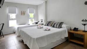 Una habitación de hotel con dos camas, una mesita de noche de madera, un teléfono y una ventana con persianas.