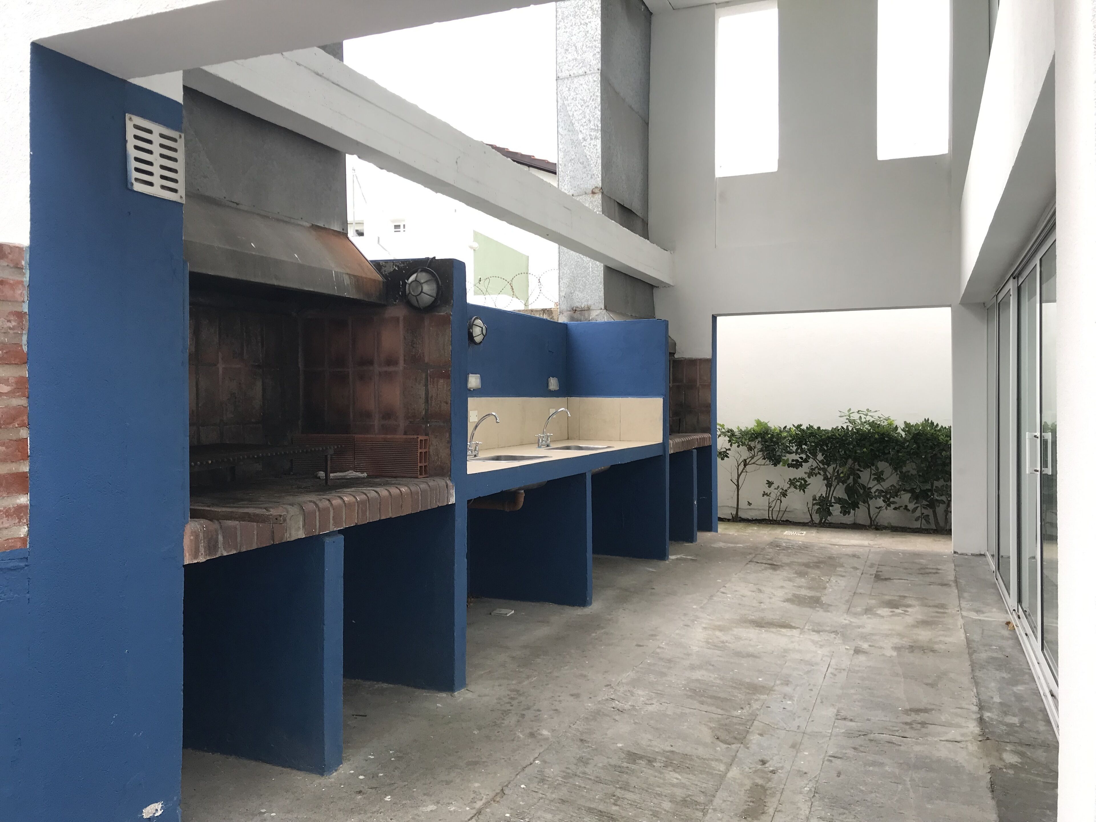 Een professionele keuken met een blauw-wit kleurenschema, met een bakoven, roestvrijstalen werkbladen en een ventilatiesysteem.