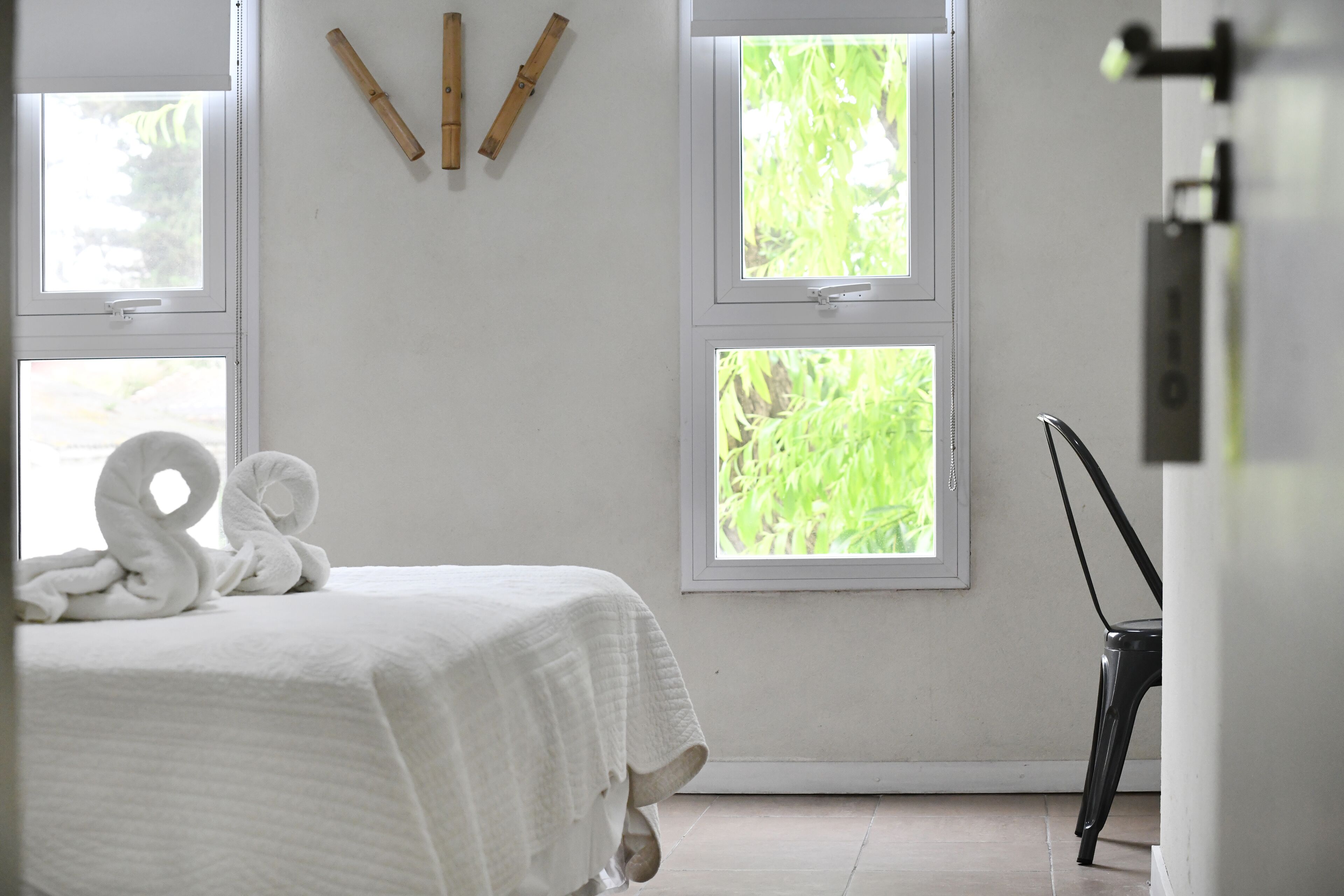 A bedroom with a bed, two windows, and a chair.