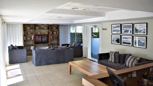 Una sala de estar moderna con dos sofás grises, una mesa de centro de madera y una estantería llena de libros y objetos decorativos.