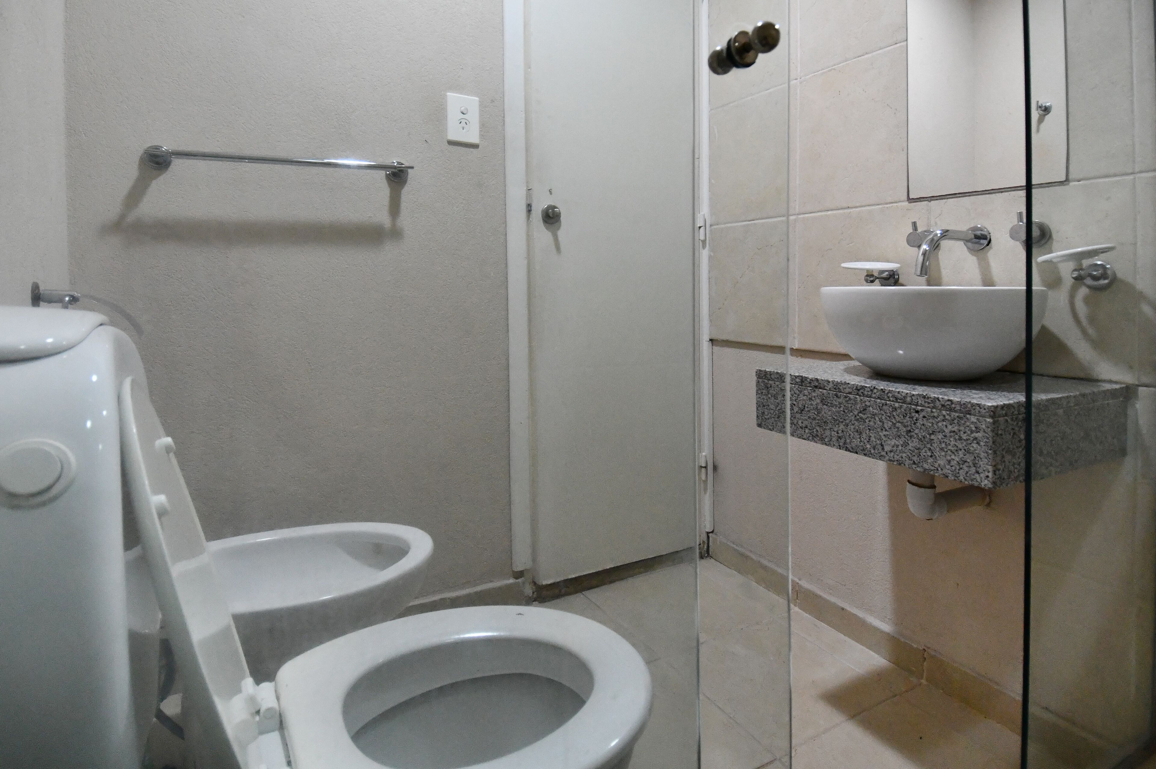 Une salle de bain équipée de toilettes, d’un lavabo et d’une douche à parois de verre.