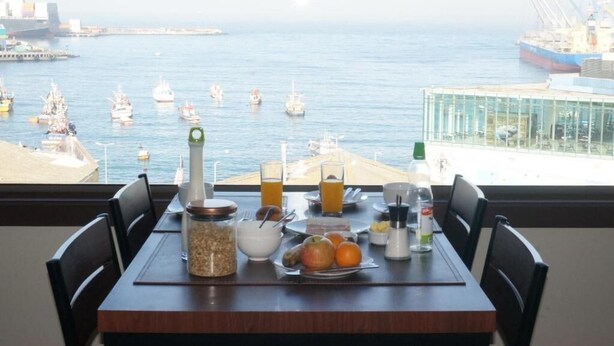 Una mesa con desayuno y vista al mar con barcos.