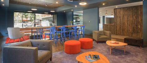 A modern lounge area with seating, a bar, and a view of the street.