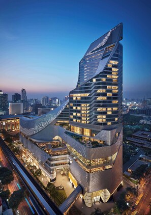 Un hôtel moderne à plusieurs étages, doté d’une façade incurvée originale, de nombreux balcons et d’une terrasse sur le toit.