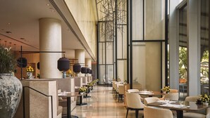 Un amplio comedor interior con techos altos, muebles modernos y ventanas grandes.