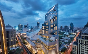 A modern skyscraper with a unique curved design, surrounded by other high-rise buildings in an urban setting. - Park Hyatt Bangkok (Bangkok)