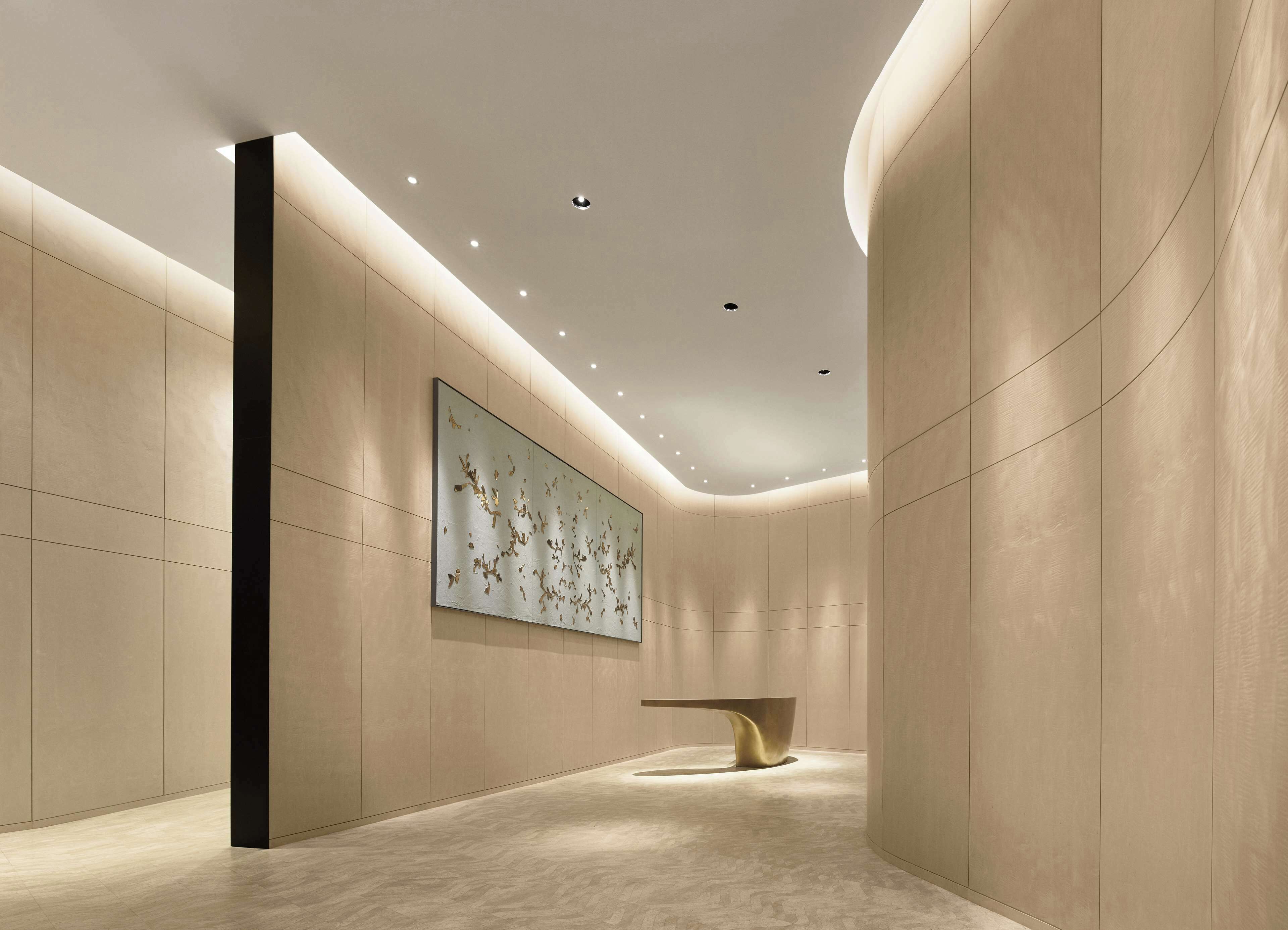 A modern interior with a minimalist design, featuring a large abstract painting on the wall, a sleek bench, and recessed ceiling lighting.
