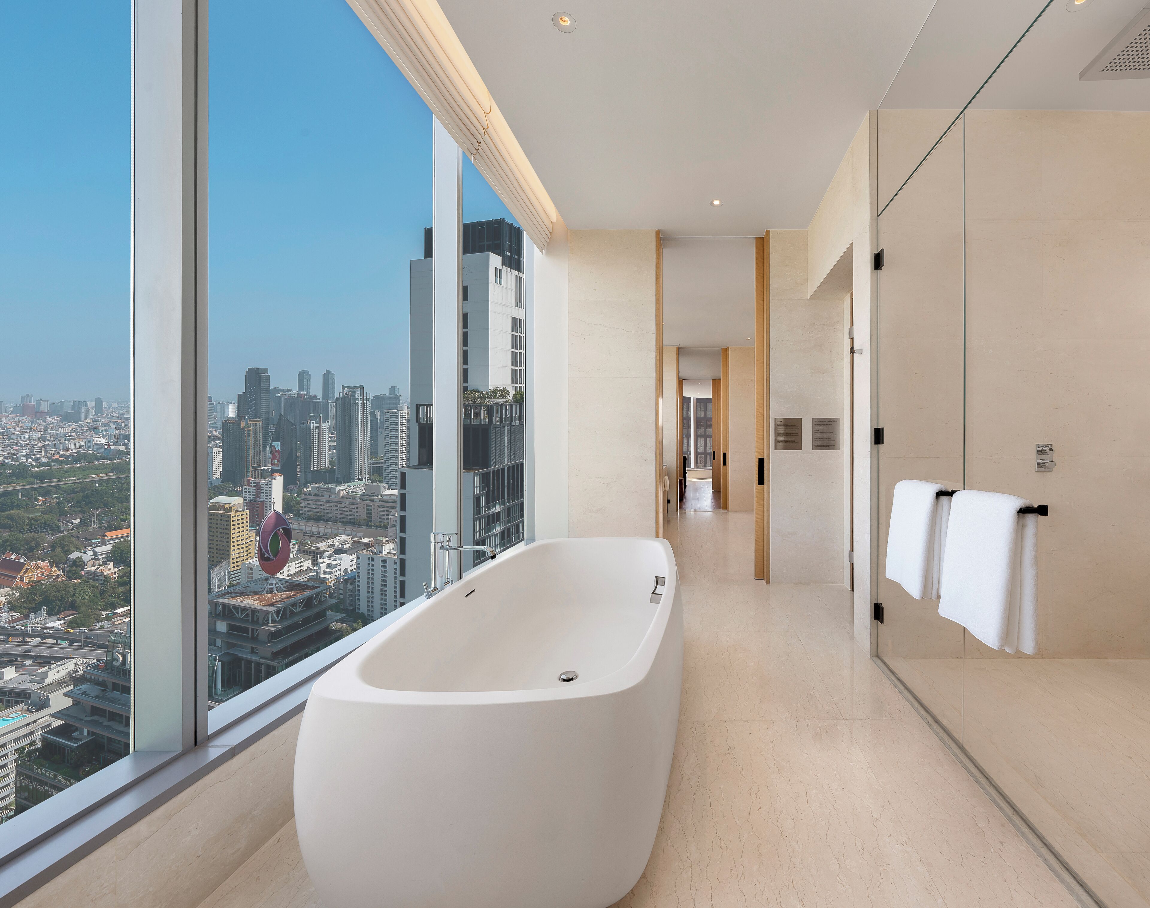 Un baño moderno con una bañera independiente, ventanas amplias y vistas a la ciudad.