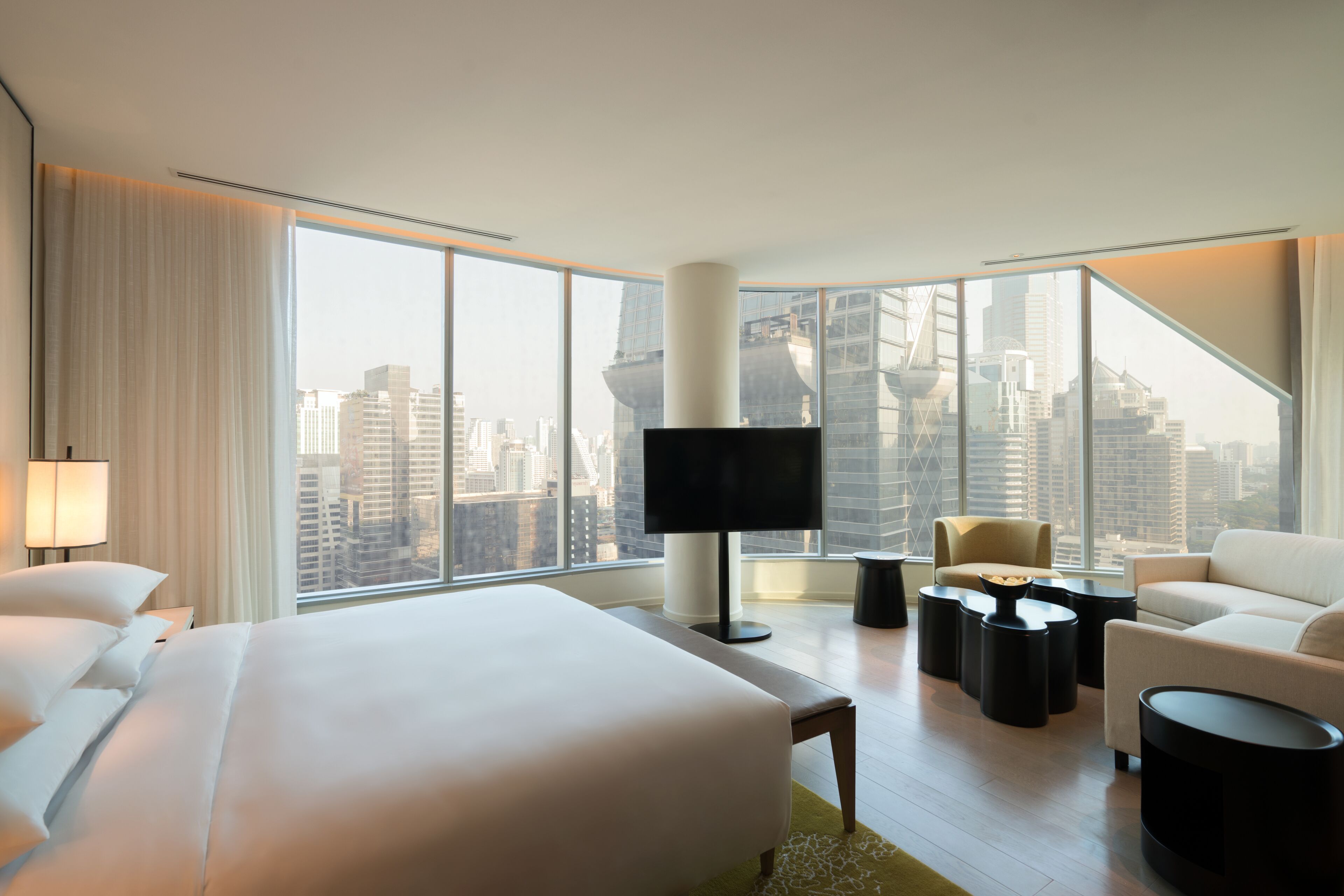 A modern hotel room with a large bed, a flat-screen TV, a sofa, and a coffee table.