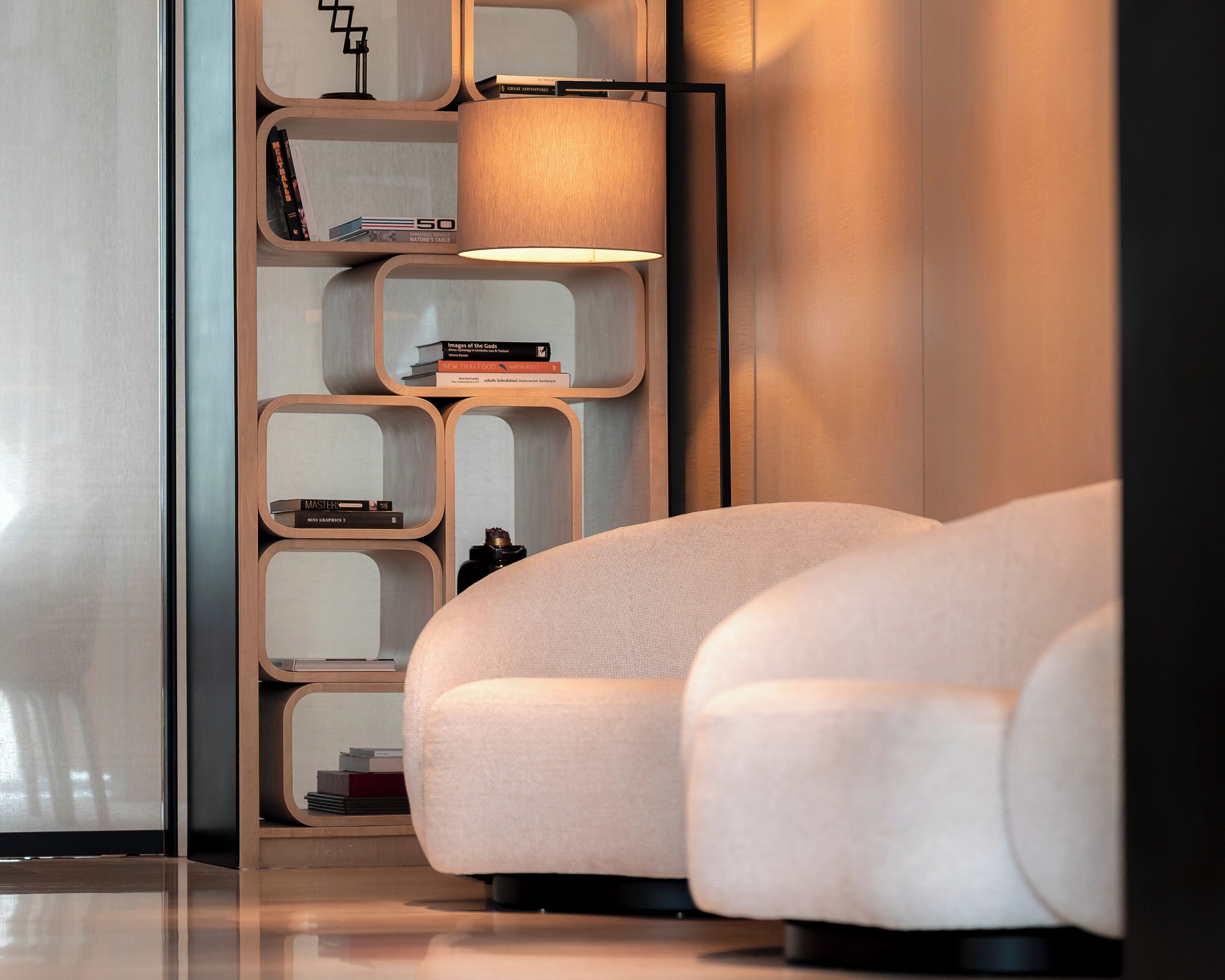 A modern interior with a sofa, a bookshelf, and a lamp.