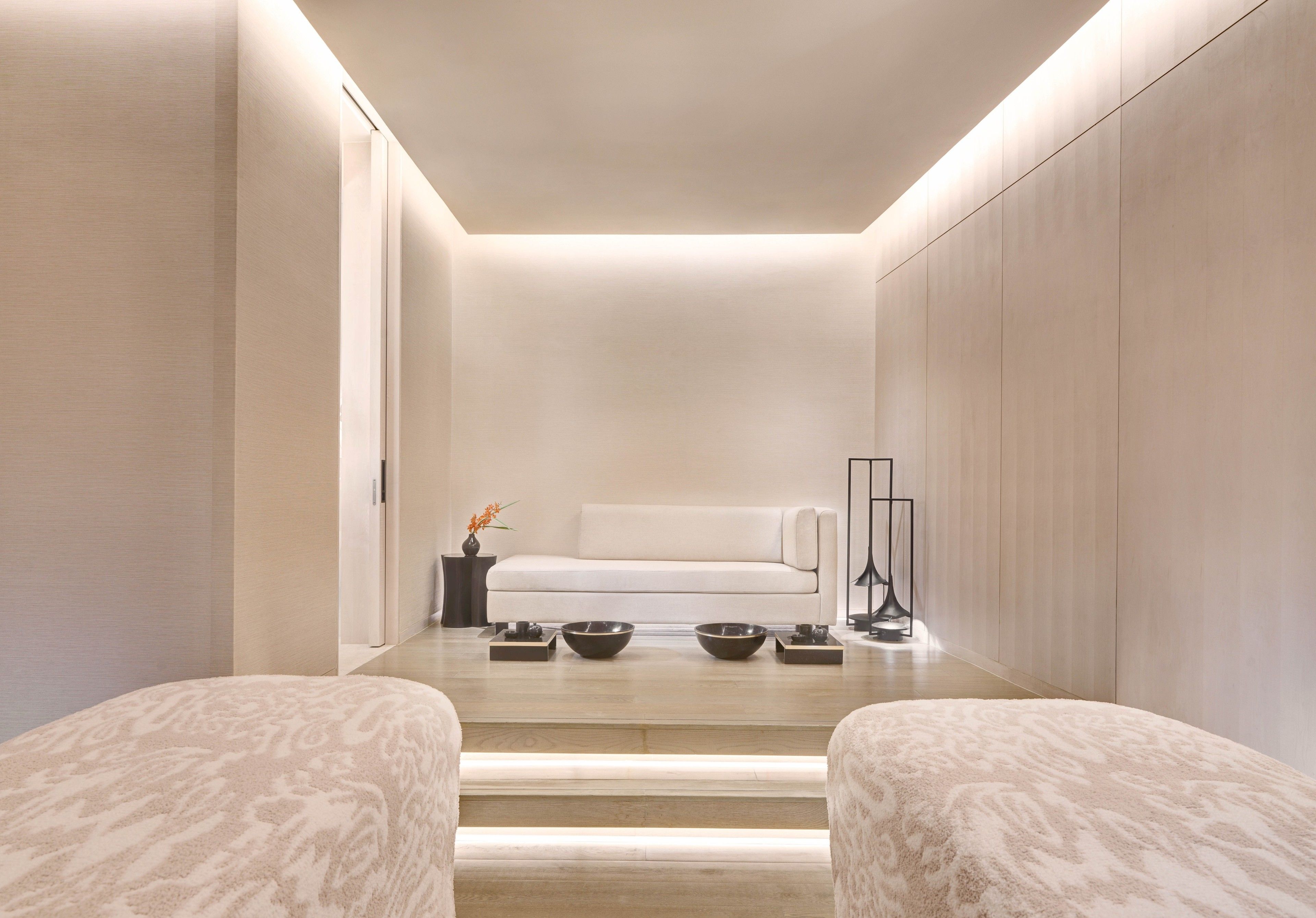 A modern, minimalist room with a sofa, two bowls, and a small table with a vase.