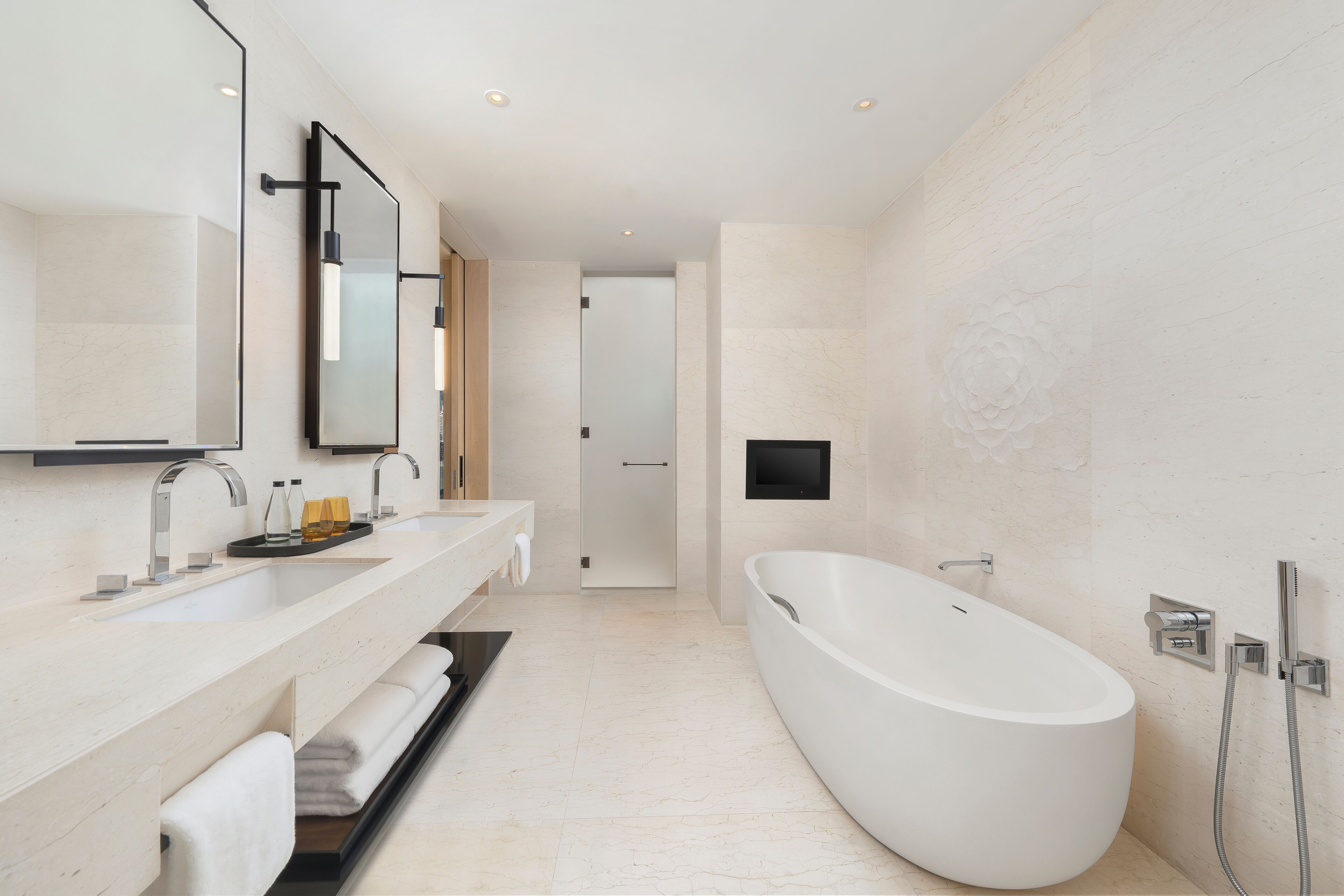 A modern bathroom with a freestanding bathtub, a large mirror, and a vanity with a sink and towel rack.