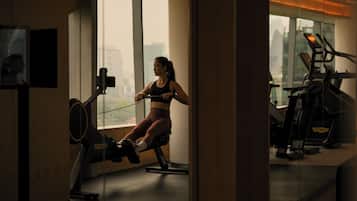 A gym with exercise equipment, large windows, and a city view.