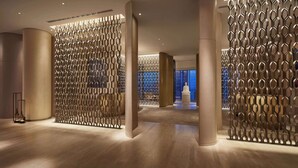 A modern interior with a patterned metal partition, large columns, and a polished floor.