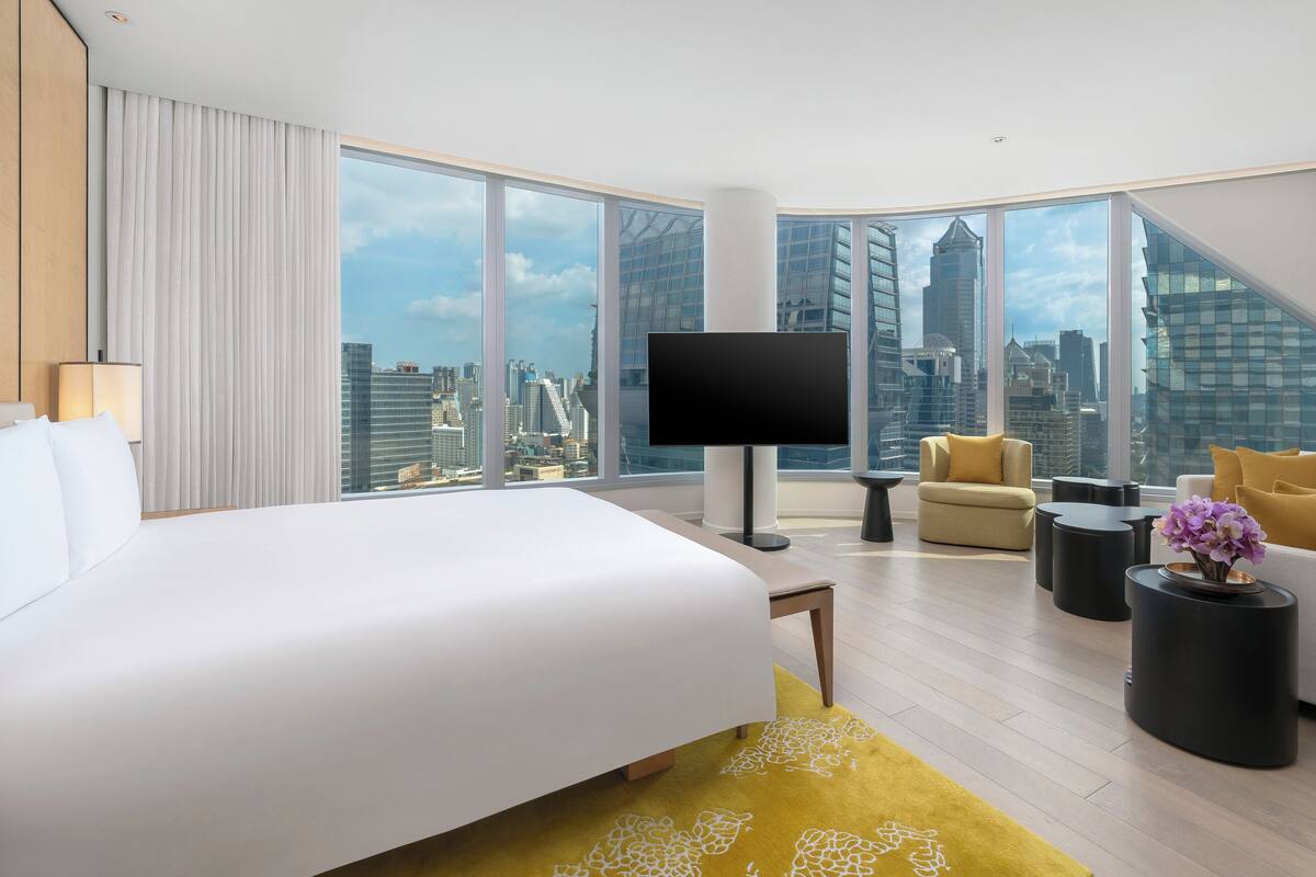 Une chambre d’hôtel moderne dotée d’un grand lit, d’un canapé, d’une télévision et offrant une vue sur la ville.