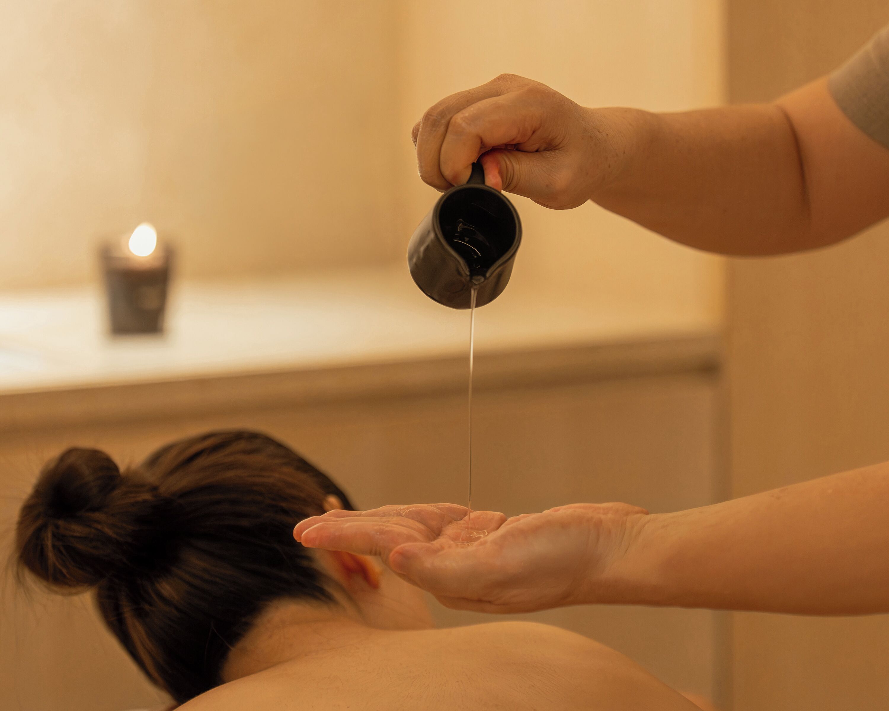 A person receiving a treatment with a liquid being poured from a container.