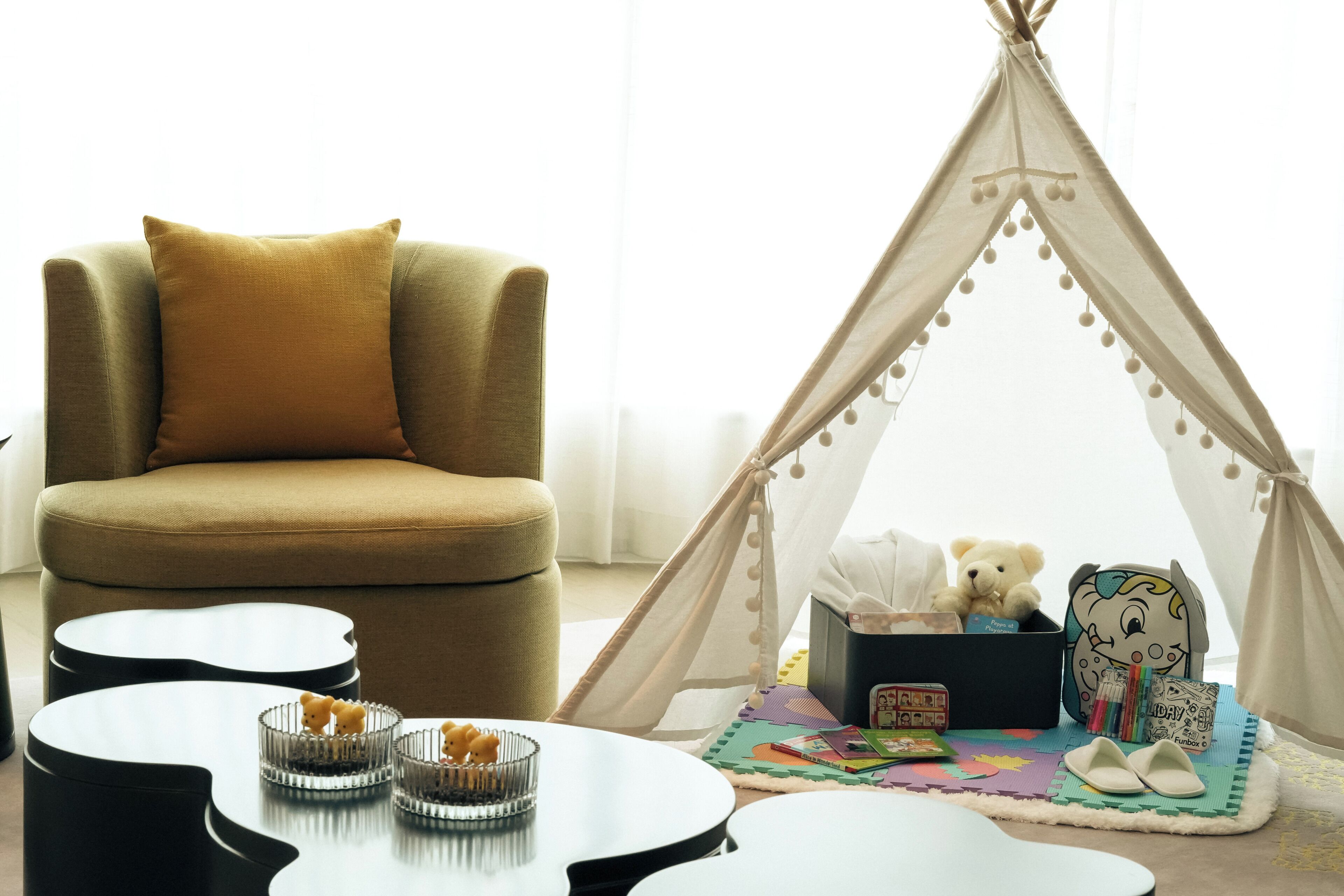 A cozy room with a sofa, a teepee, and a play area with toys and books.