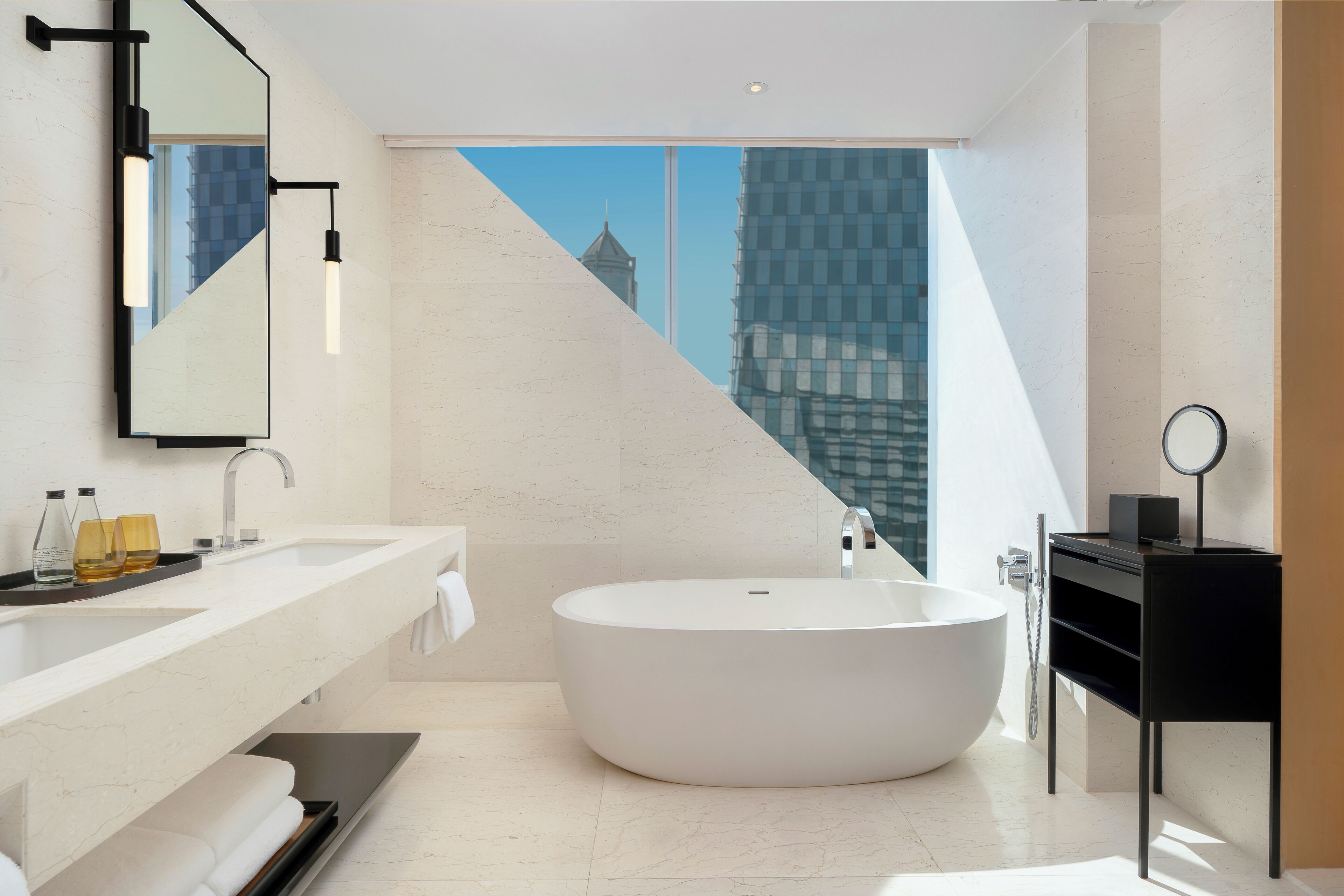 A modern bathroom with a large bathtub, a double sink vanity, and a large mirror.