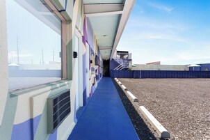 Um corredor com carpete azul, corrimão branco e vista do céu.