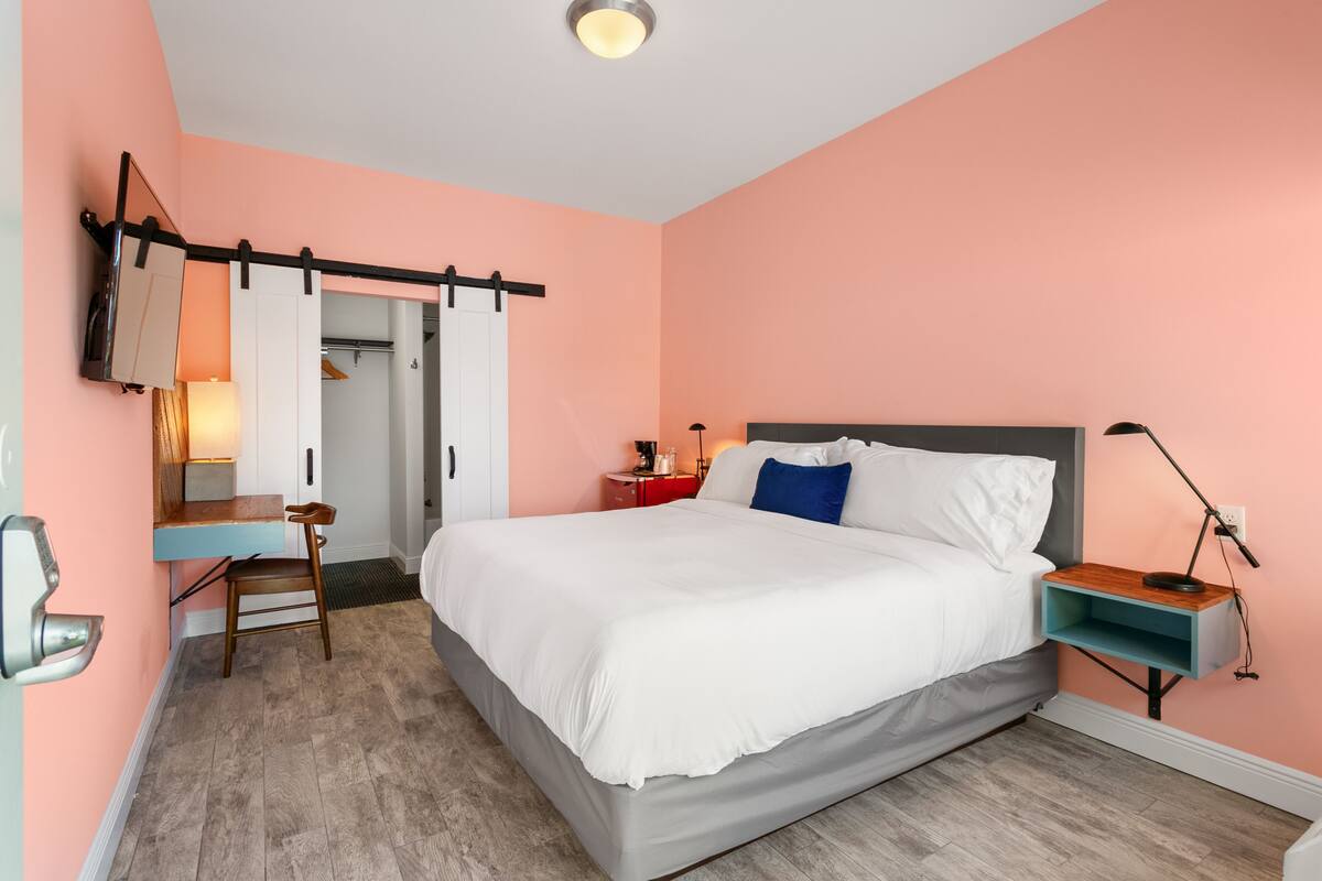Quarto com cama, mesa de cabeceira, cadeira, escrivaninha e porta com sistema deslizante.